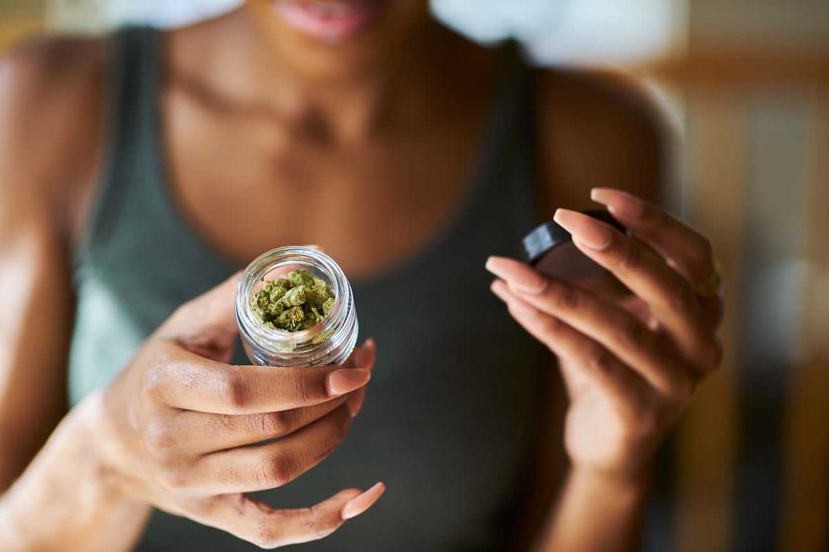 woman holding cannabis flower container