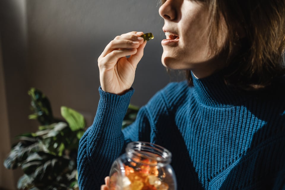 woman in blue sweater eating CBD gummies