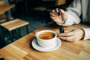 Women adding CBD oil to Coffee